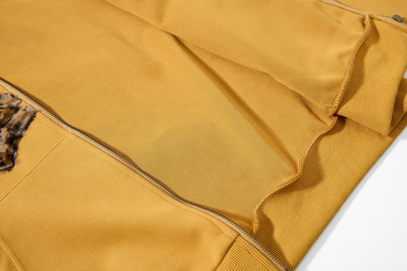 Close-up of mustard yellow hoodie side seam, zipper, and sleeve hem