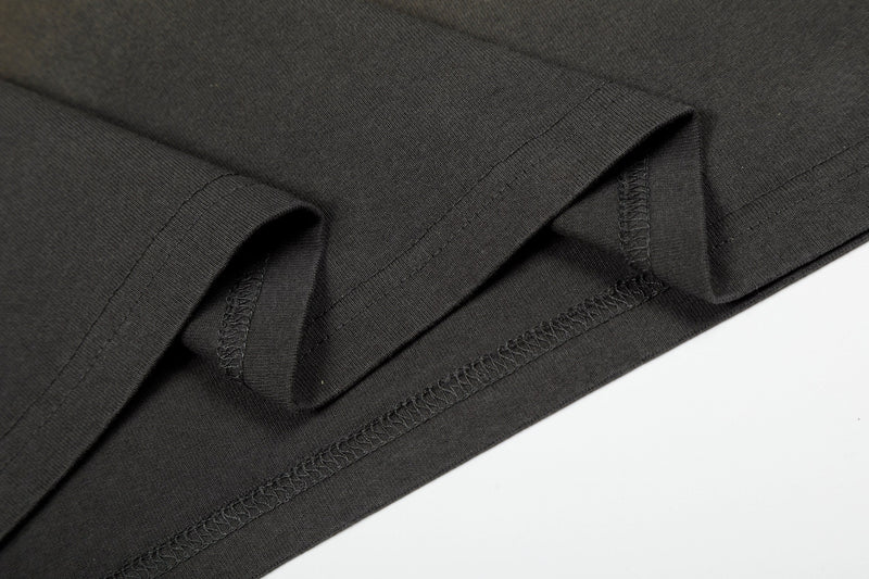 Close-up of black vintage washed T-shirt sleeves and hem with visible stitching on a clean white background