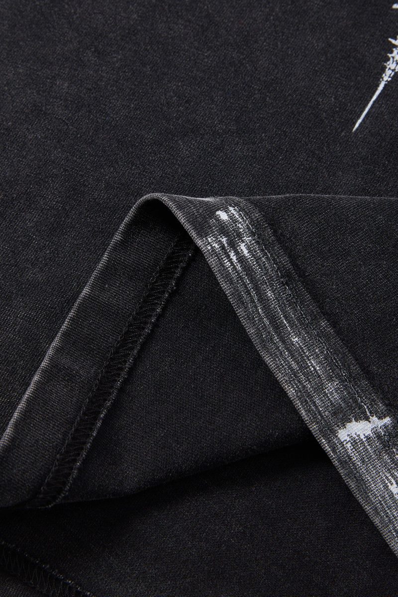Close-up of black washed T-shirt fabric with distressed white spine graphic and raw streetwear texture