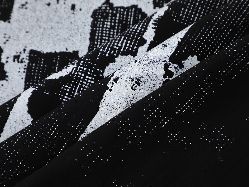 Close-up of black-and-white graphic plaid shirt fabric with bold abstract pattern and textured streetwear style