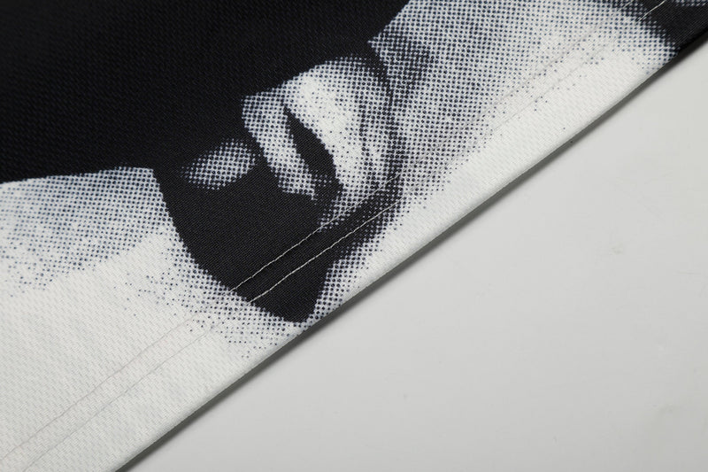Close-up of black and white mesh soccer jersey fabric with bold graphic print and stitched hem