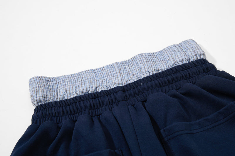 Close-up of layered plaid and navy elastic waistbands on the athletic shorts