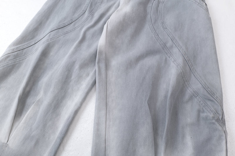 Close-up of curved side seam details on light gray washed denim