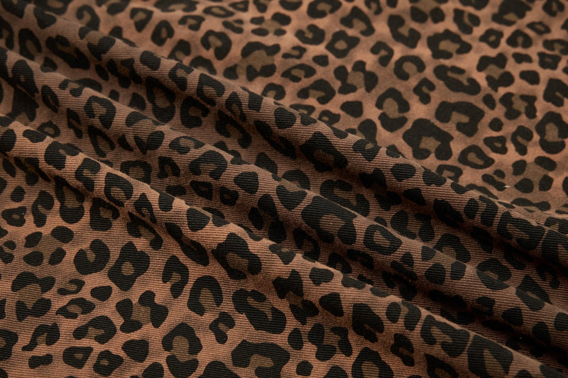 Close-up of brown leopard print shirt fabric with black spots and soft folded texture