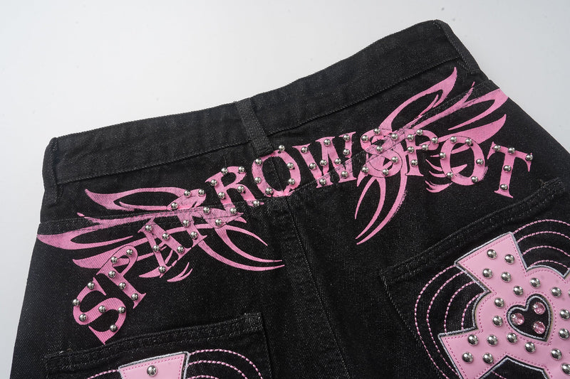 Back waistband close-up on black jeans with pink graphic print and silver studs