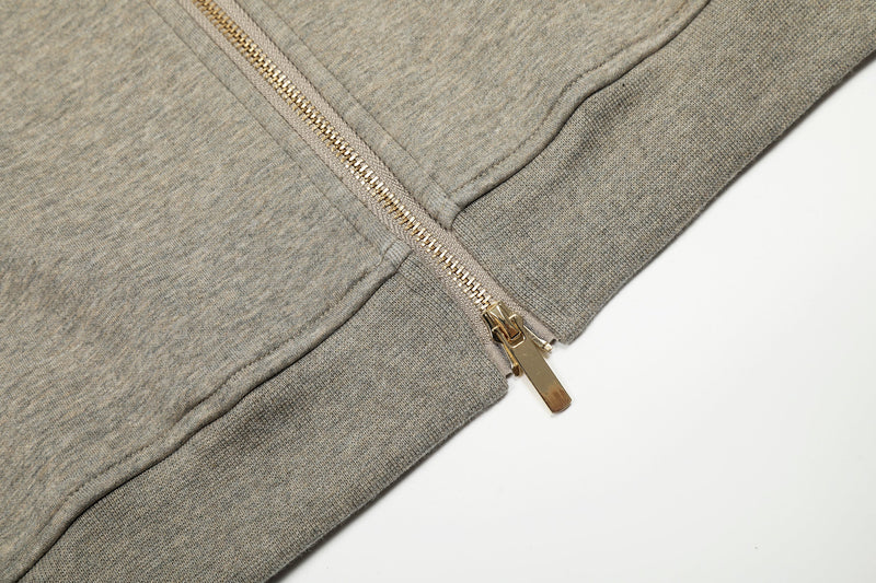 Close-up of beige hoodie hem with gold zipper and ribbed knit waistband