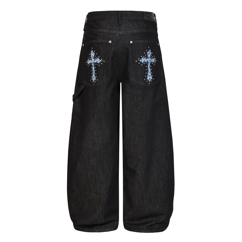 Back view of black wide-leg jeans with flap back pockets and blue cross appliqués