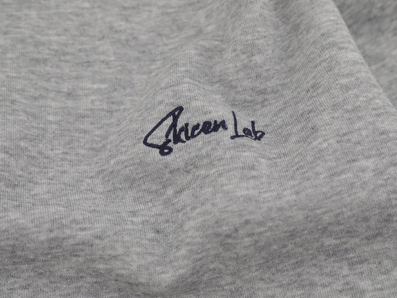 Close-up of gray chest logo on soft knit sweatshirt fabric
