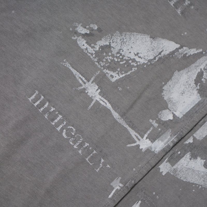 Faded portrait graphic and partial text print on washed grey tee fabric close-up