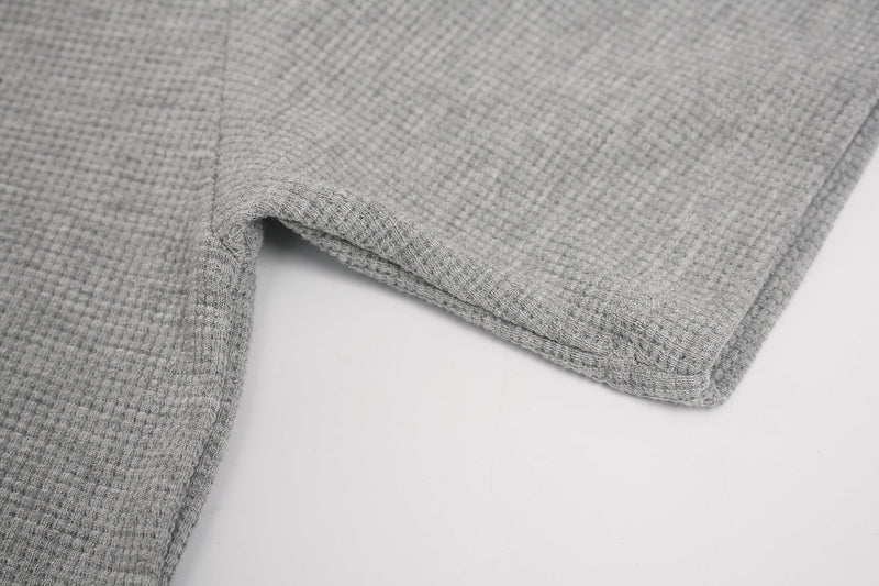 Close-up of gray waffle-knit tee fabric with stitched hem and textured sleeve detail