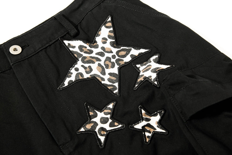 Close-up of black cargo pants with leopard star appliqués near the waist