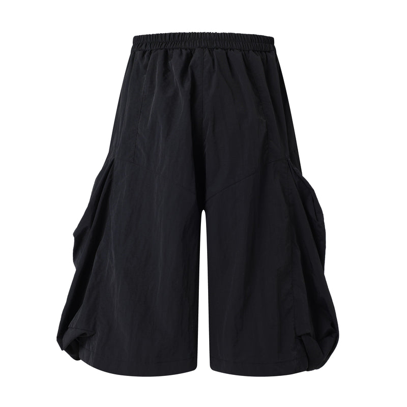 Black wide-leg shorts, back view with elastic waistband and draped side volume