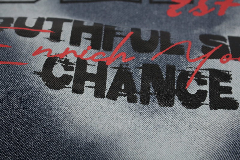 Close-up of washed denim-look graphic T-shirt with bold black typography and red spray-paint style lettering