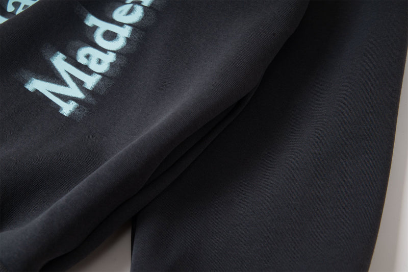 Close-up of black hoodie sleeve and blue letter print on soft fabric