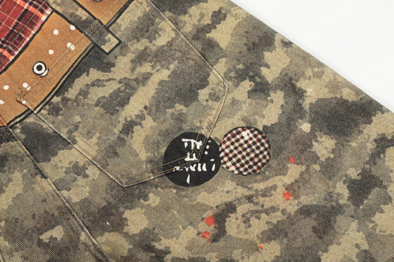 Close-up of back pocket area with camo denim, stitched flap, and small graphic patches