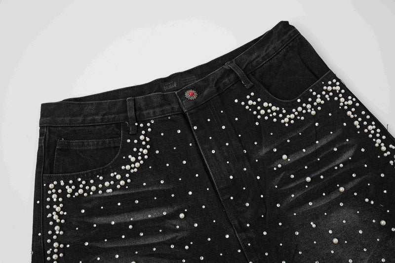 Angled front view of black denim shorts with pearl stud trim