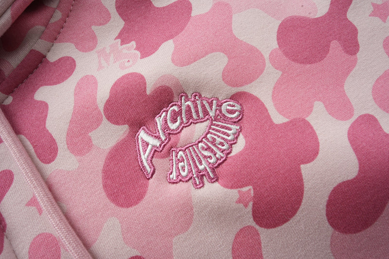 Close-up of embroidered Archive logo on pink camo hoodie chest