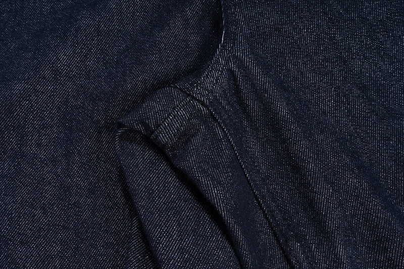 Close-up of side seam and angled cargo pocket detail on dark indigo denim shorts