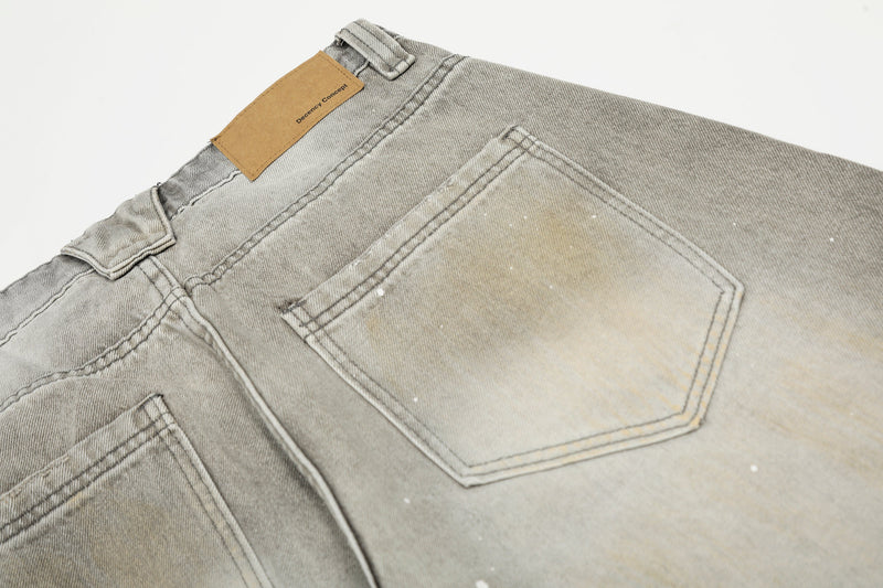 Back pocket close-up of gray jeans with tan waistband patch and faded wash
