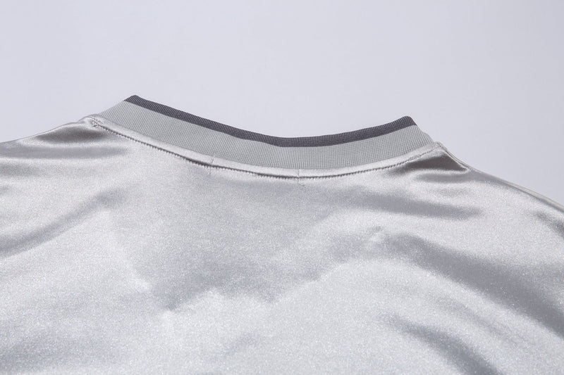 Close-up of light gray ribbed V-neck collar on long sleeve jersey top