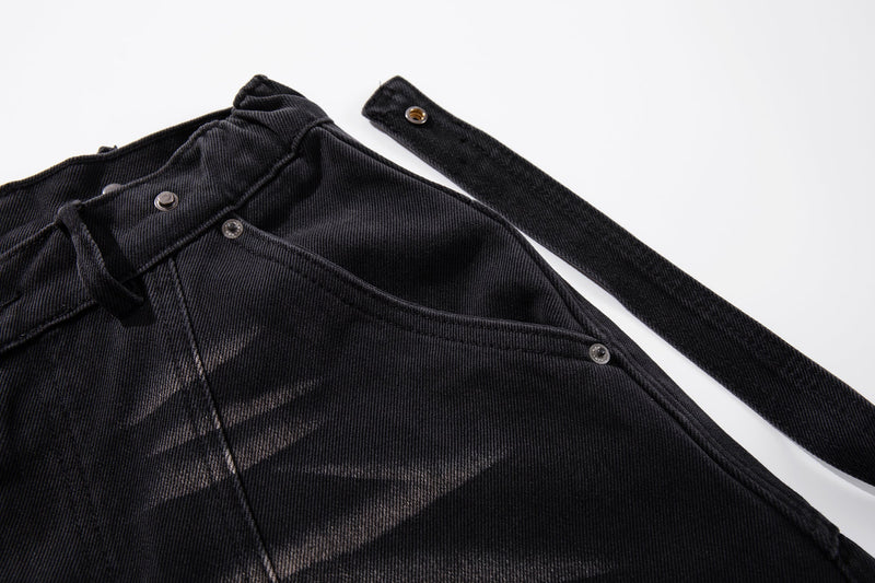 Close-up of upper waistband and strap detail on dark washed denim jeans