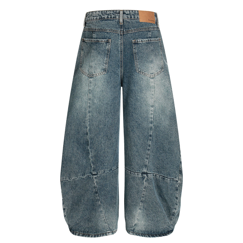 Back view of blue wide-leg jeans with patch pockets, tan label, and faded wash