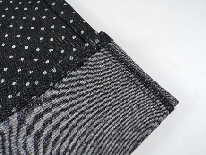 Close-up of turn-up cuff and hem stitching on black polka-dot denim pants