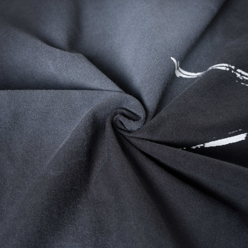 Close-up of dark grunge graphic tee fabric with white star print and soft folded cotton texture