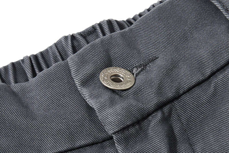 Close-up of dark gray pant waistband with button, belt loop, and elastic back