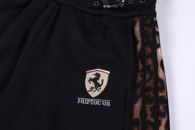 Close-up of embroidered crest and text on black shorts beside leopard side stripe