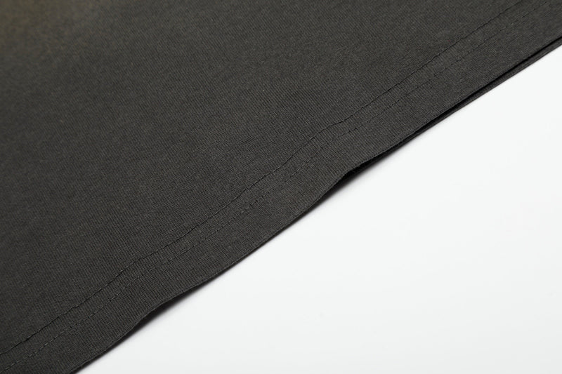 Close-up of a black vintage washed graphic T-shirt hem with visible stitched seam and soft streetwear fabric texture