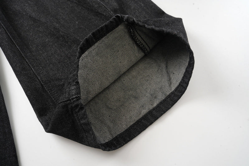 Cuffed hem of black denim pants showing the inside seam