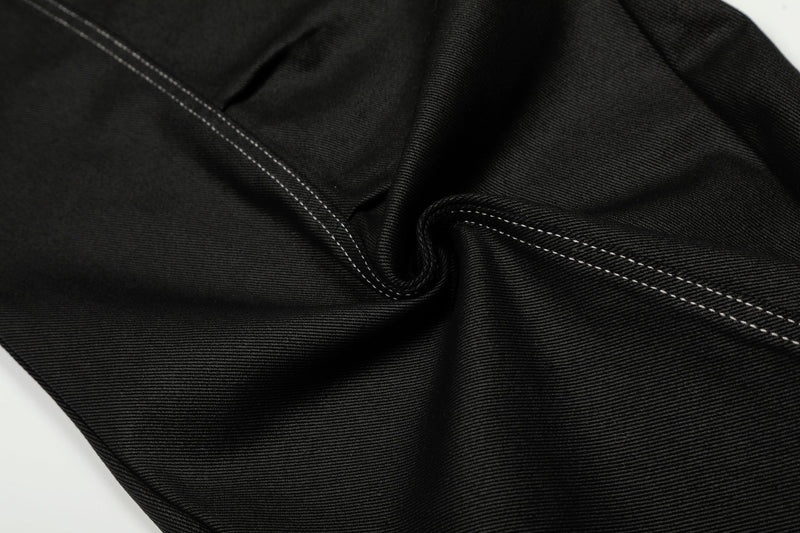 Close-up of black denim fabric with diagonal contrast stitching and a soft fold