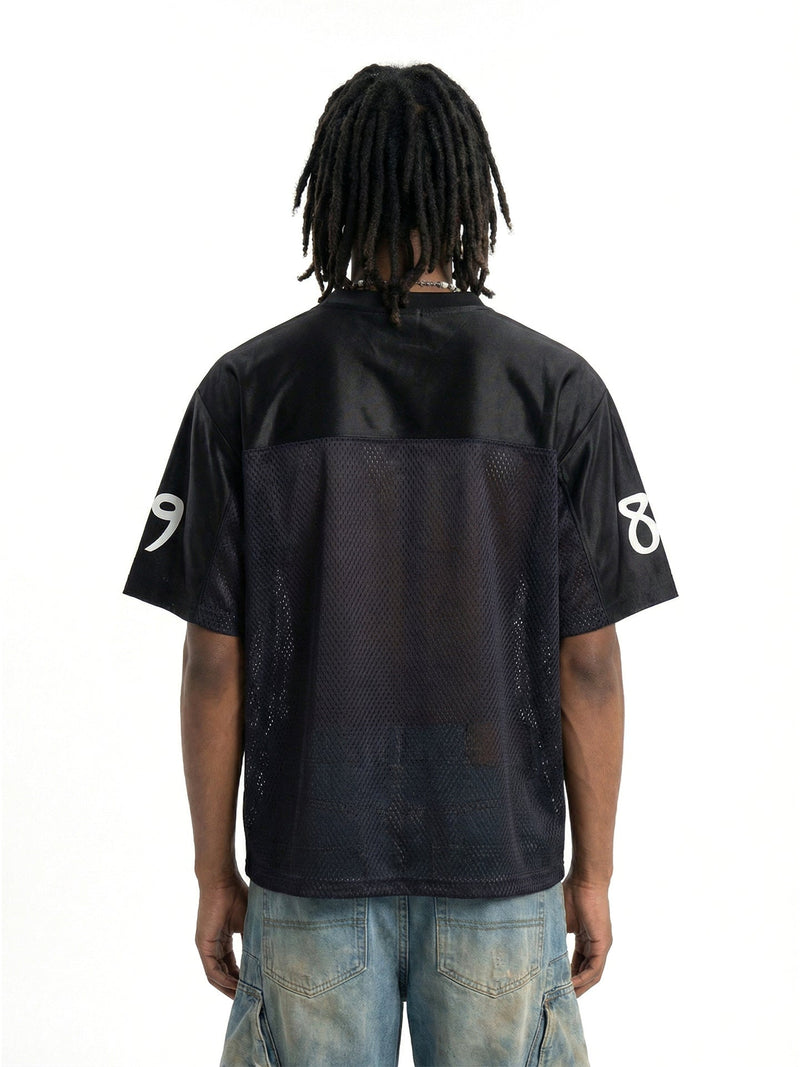 Back view of black mesh football jersey with white 89 sleeve numbers and denim jeans on model