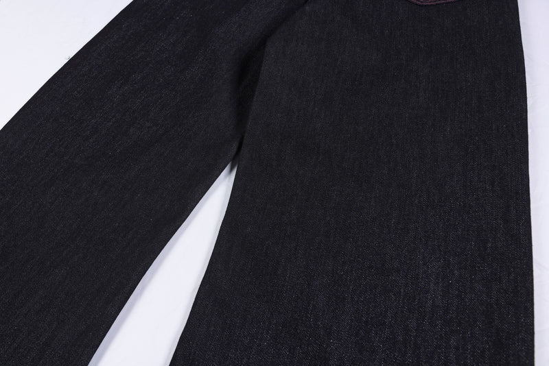 Close-up of the wide leg fabric on black denim pants with pink hem stitching