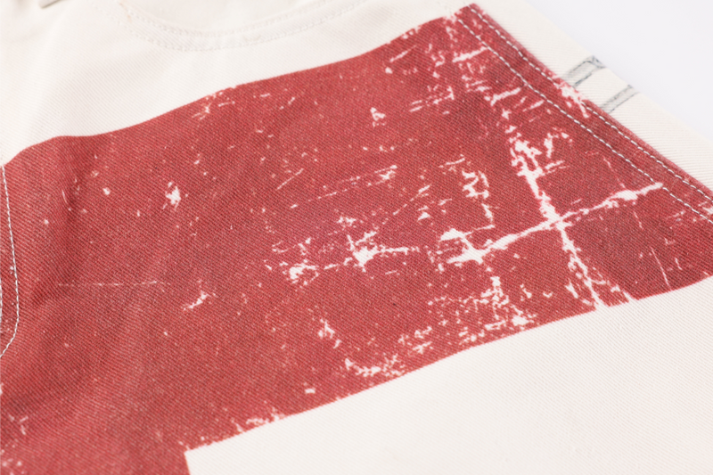 Close-up of red distressed block print on cream denim