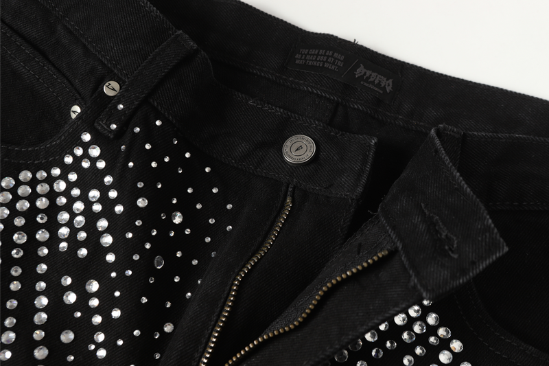 Close-up of black jeans front with zipper fly and rhinestone detailing