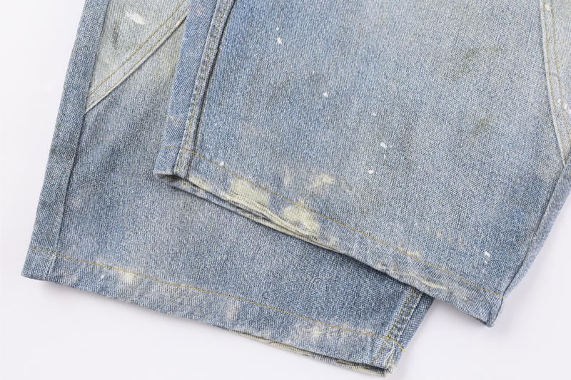 Close-up of stacked pant hems showing faded, distressed light wash denim
