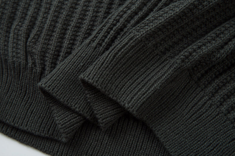Close-up of dark ribbed knit sweater sleeve cuff and textured knit pattern