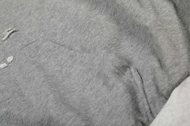 Close-up of heather gray hoodie body with distressed fabric texture and small holes