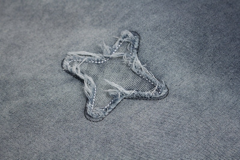 Distressed star patch on vintage washed gray denim-style streetwear T-shirt fabric close-up