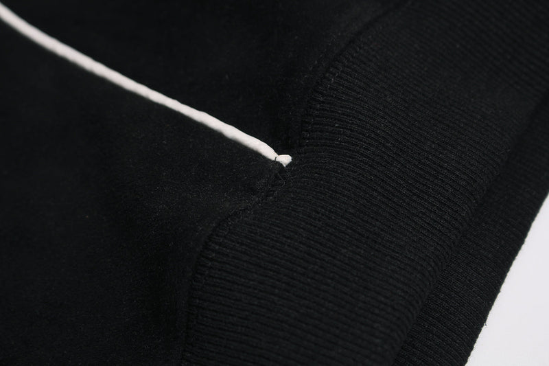 Close-up of black hoodie seam with white piping detail