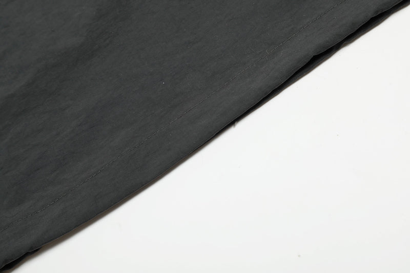 Close-up of black nylon jersey fabric with visible stitching and clean hem on a white background