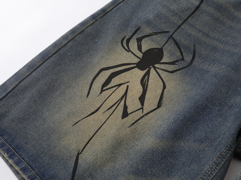 Close-up of spider web graphic printed on faded blue denim fabric