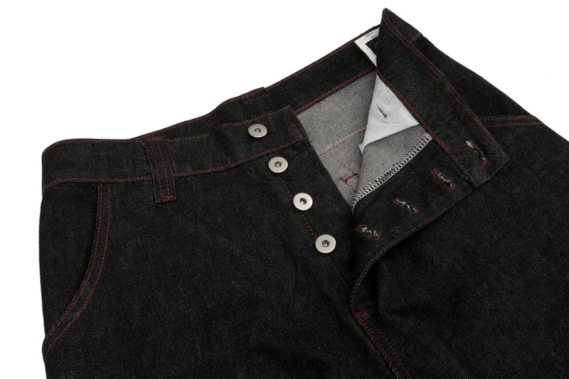 Close-up of open waistband on black denim pants showing inner lining and button fly