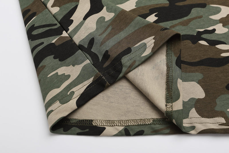 Close-up of a camo polo shirt hem with stitched seams and layered camouflage fabric in green, tan, black, and brown