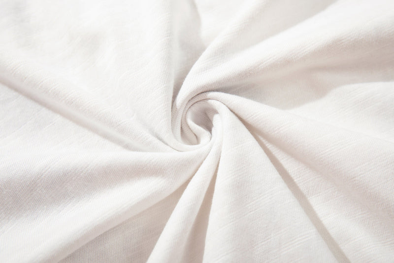 White cotton t-shirt fabric close-up with soft folds and a smooth spiral texture