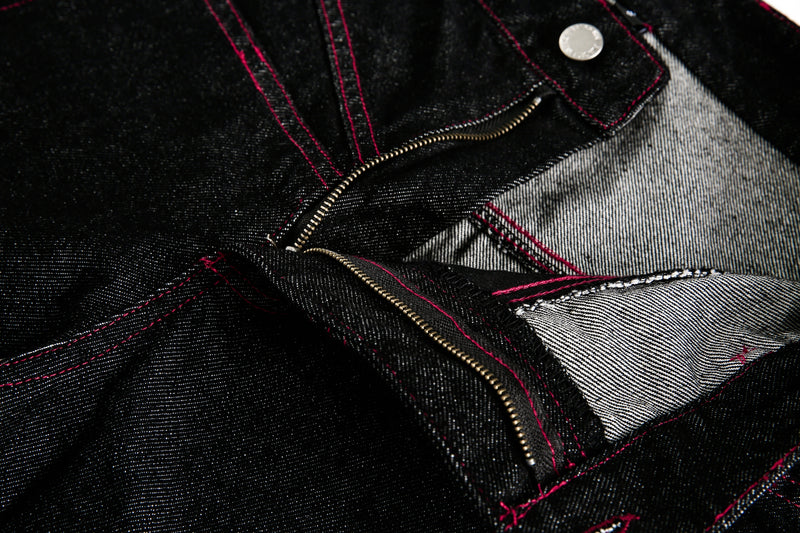 Close-up of black denim fly and inside seam with red stitching
