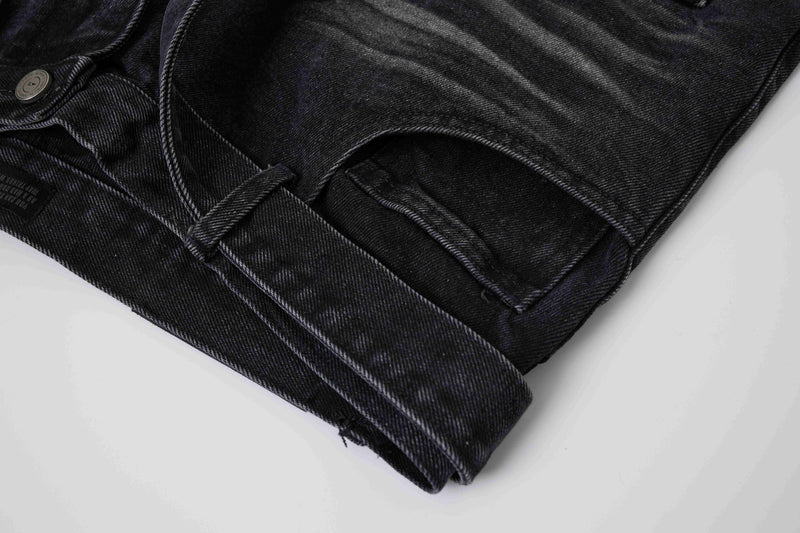 Close-up of black denim shorts hem with folded cuff and seam detail