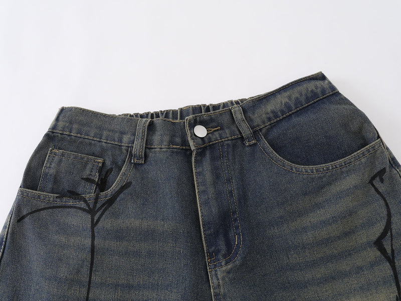 Close-up of waistband and front pockets on blue denim shorts with spider web print